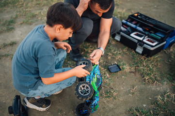 A father and son are fixing remote control car together. Teamwork.