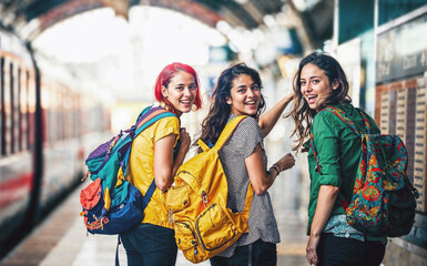 Excited teenage girls at a train station, embarking on their first gap year adventure together.