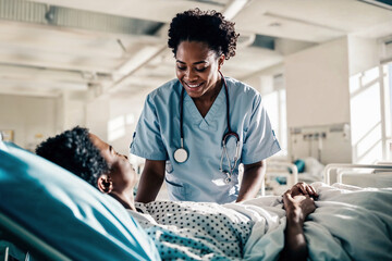 African American nurse providing care and comfort to an elderly patient in a brightly lit hospital ward, symbolizing empathy in healthcare.

 - obrazy, fototapety, plakaty