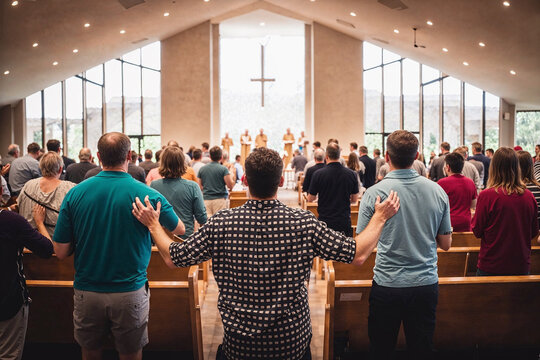 Back view of a diverse congregation standing together in worship inside a modern church, a scene of community and spirituality.

