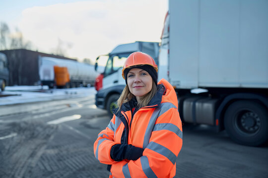 Worker in high-visibility gear standing by trucks