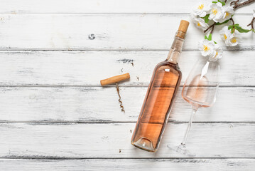 Rose wine in a bottle and glasses, a corkscrew and a decorative cherry branch on a white wooden table. Top view, flat lay, copy space. - 766612880