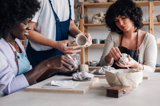Interracial pottery class students with clay in hands learning clay work