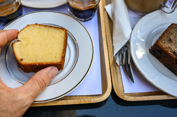 Paris, France. A rich breakfast with typical desserts and cappuccino and coffee. View from above. The hand grabs the slice of cake.