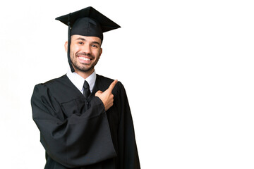 Young university graduate man over isolated chroma key background pointing to the side to present a...