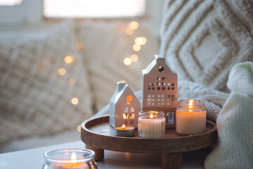 Winter home aromatherapy, cozy atmosphere. Burning aroma candles on wooden tray, knitted blanket....