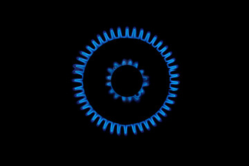 Gas burns blue on black background. Heat and Mirage above the gas hob switched on. Top view of a kitchen burner glowing at night, close-up. Natural gas concept. The gas stove is on