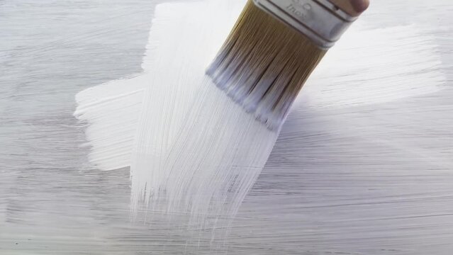 Close-up painting of wood with white paint. Home renovation and DIY concept.