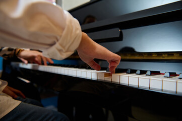 Musician pianist puts fingers on piano keys, playing piano, enjoying performance of classical melody during music lesson