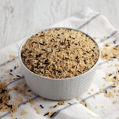 Raw Organic Wild Rice in a Bowl on a white wooden background, side view.