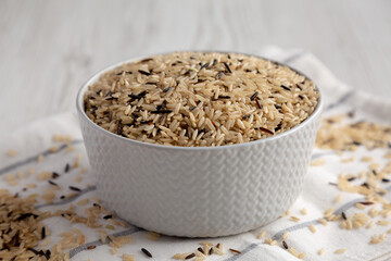 Raw Organic Wild Rice in a Bowl on a white wooden background, side view.
