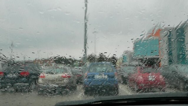 a parking lot near a large shopping center in the background. view from the interior of the car. raindrops on the tinted glass of the car. rain background. drops run down the glass. 