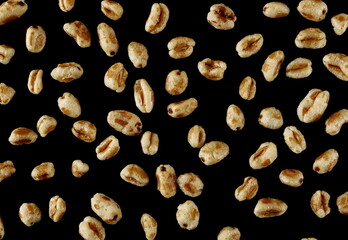 Puffed wheat cereal flakes isolated on black, top view - 766629467