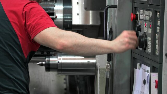 Worker pressing buttons on CNC machine control board in factory. High quality 4k footage