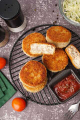 Grid of tasty meat cutlets with sauce on grey background