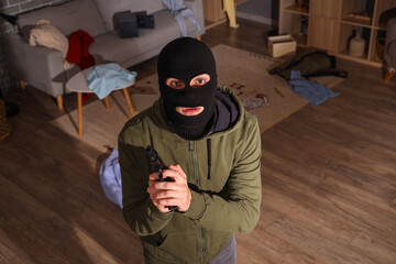 Male thief with gun in room at night