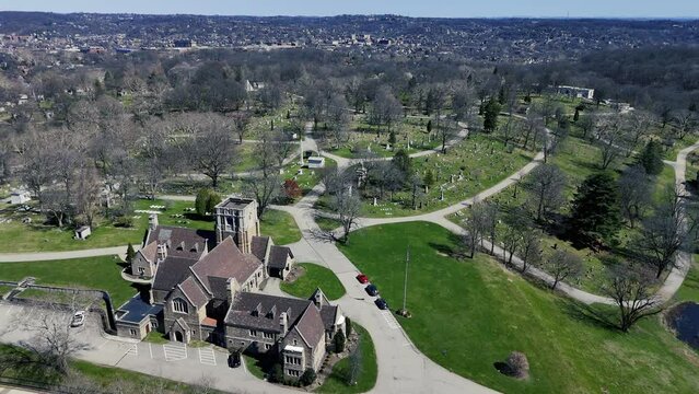 A daytime early spring aerial establishing shot of Homewood Cemetery in Pittsburgh, Pennsylvania.  	