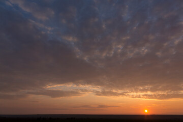 Landscape with bloody sunset. Panorama. Tragic gloomy sky. The last flashes of the sun on the storm clouds.