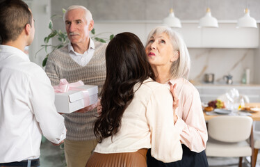 Fototapeta premium Delighted mature parents taking in young family members who came to visit them in their house