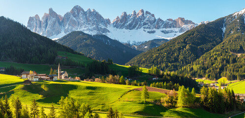 Panoramic view of sunny landscape with Santa Maddalena village against the Geisler mountains covered with snow at sunrise, Val Di Funes in Dolomites mountains, South Tyrol, Italy.