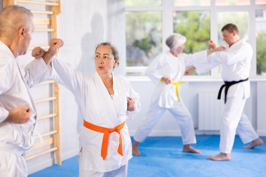 Senior karate practitioner engage in fierce fight, perseverance during martial arts discipline, middle-aged teacher and mature followers. Work on yourself, increase endurance, determination, courage