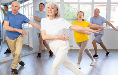 Cheerful elderly woman attending group choreography class, learning modern dynamic dances. Concept...