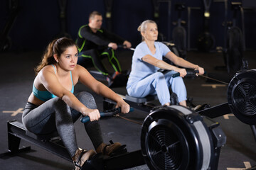 Fototapeta na wymiar Athlete woman works on the rowing simulator in gym