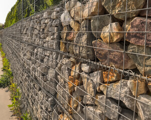 Ogrodzenie (ściana) wykonane z kamieni i siatki stalowej.Ciekawe architektonicznie ogrodzenie z paneli siatkowych wypełnionych fragmentami skał.