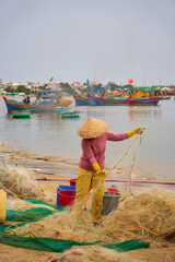 A woman folds fishing nets in Vietnam.