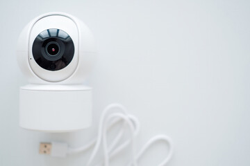 Modern white security camera on a table by a window. Suitable for security system advertisements or residential settings