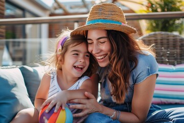A brunette mother in a hat and her young daughter smiling and enjoying themselves together on a terrace