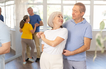 Mature man in dance hall with female partner and dances Latin rumba. Hobby, healthy lifestyle...