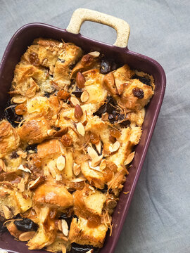 Homemade bread pudding made with croissants, milk, egg, almond, raisins, dark chocolate, and shredded cheese. Top view.