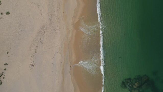 Aerial top down view moving above a sandy beach shore with small waves, Atlantic ocean, natural scene, Spain, Galicia, Rias Baixas, Pontevedra province
