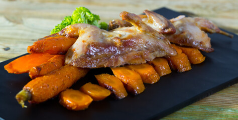 Dish of tasty quail of teriyaki with carrots, fried on a grill, served with greens