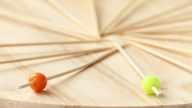 Circular motion: man puts wooden sticks with multicolored round for pinchos tips rotate on a wooden board