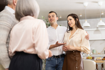 Middle-aged son introduces his girlfriend to elderly parents. Upset parents look disapprovingly at...
