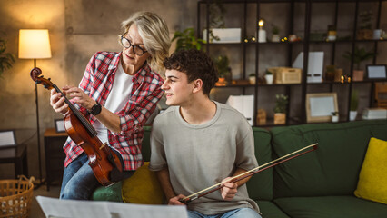 Young man learn how to play violin under instruction mature professor