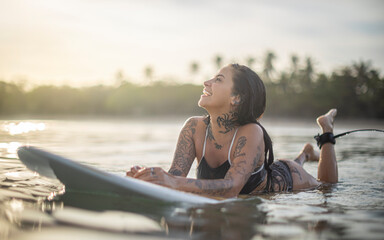 Happy tattooed girl surfing early in the morning