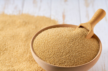 Grains amaranth are scattered out of the wooden bowl on a light table, selective focus. - obrazy, fototapety, plakaty