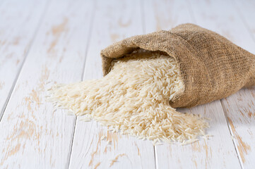 Long rice basmati in sack on a light table, selective focus.