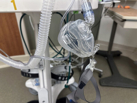 A bi-pap mask hangs from the machine in a hospital emergency room.