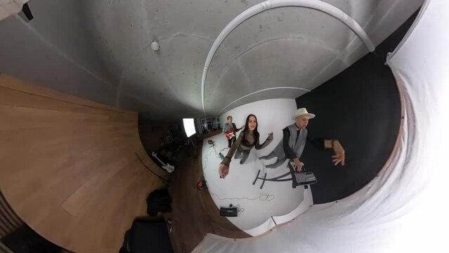 Female stylish singer rehearsing song with glam rock band members in studio and recording process using action camera 360