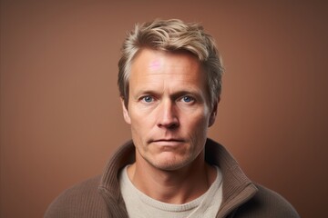Portrait of a handsome man with blond hair on a brown background - obrazy, fototapety, plakaty