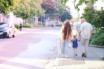 man and woman with child, happy family together walks along city street, blurred overexposed image,...