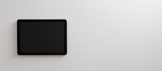 A black tablet is placed alone against a white backdrop, with a blank screen providing space for text.