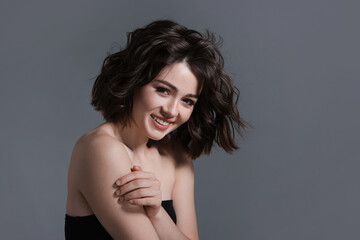Fototapeta premium Portrait of beautiful young woman with wavy hairstyle on grey background. Space for text