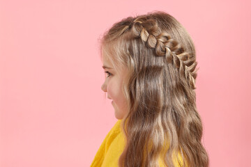 Cute little girl with braided hair on pink background