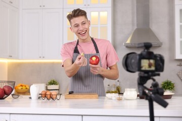 Smiling food blogger explaining something while recording video in kitchen