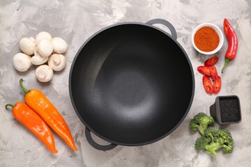 Wok and different products on grey textured table, flat lay